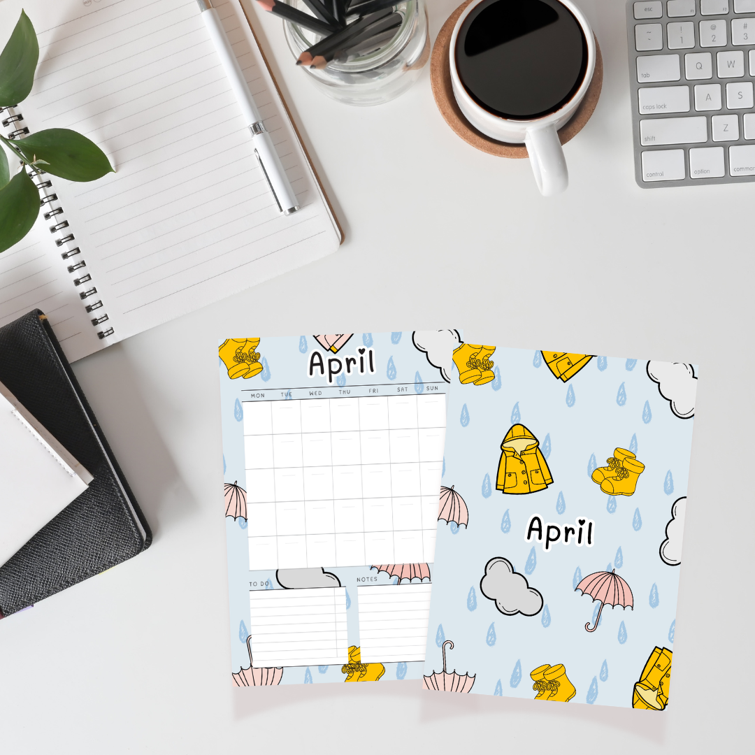 April-themed planner with raincoat, umbrella, and flower design on a desk with office supplies.