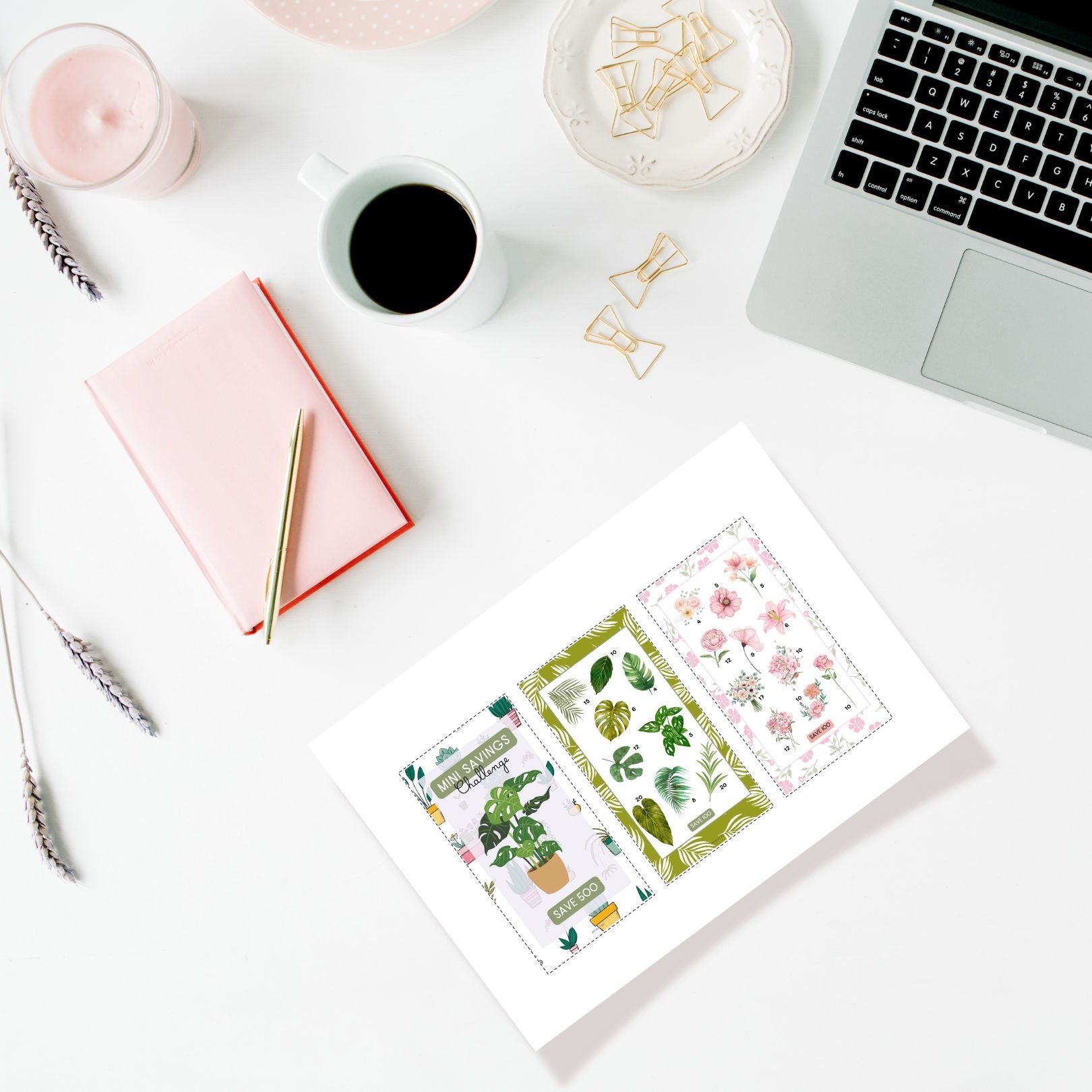 Desk setup with laptop, notebook, coffee, and decorative cards on a white surface