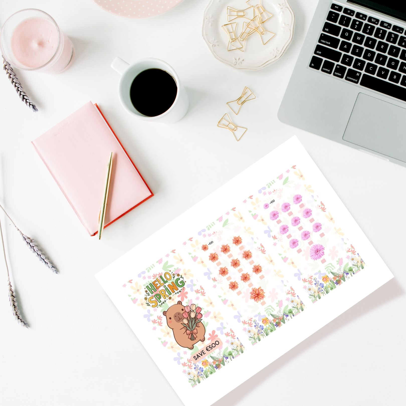 Desk setup with a laptop, notebook, coffee, and stationery items on a white surface.