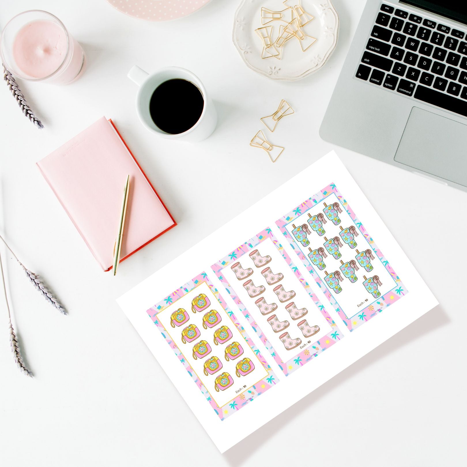 Desk setup with a laptop, coffee, notebook, and decorative stickers on a white surface.